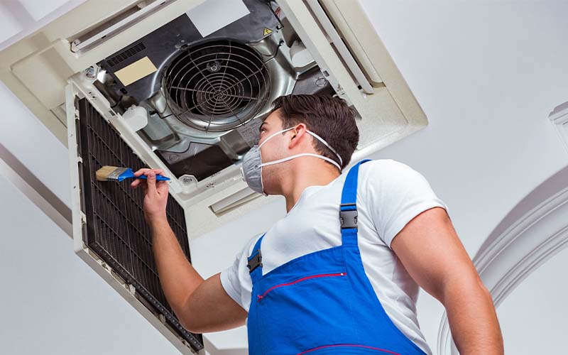 AC tech repairing ceiling air conditioning unit