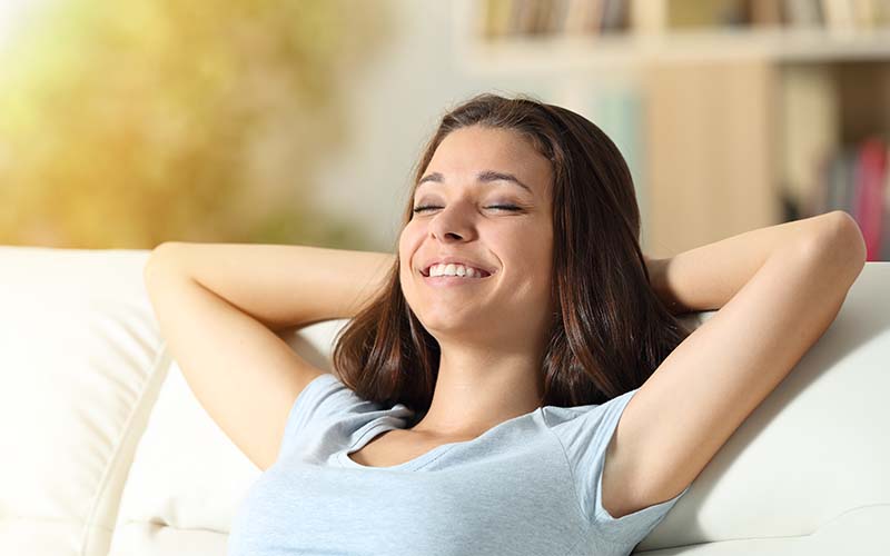 Happy relaxed girl resting at home on a couch enjoying clean air
