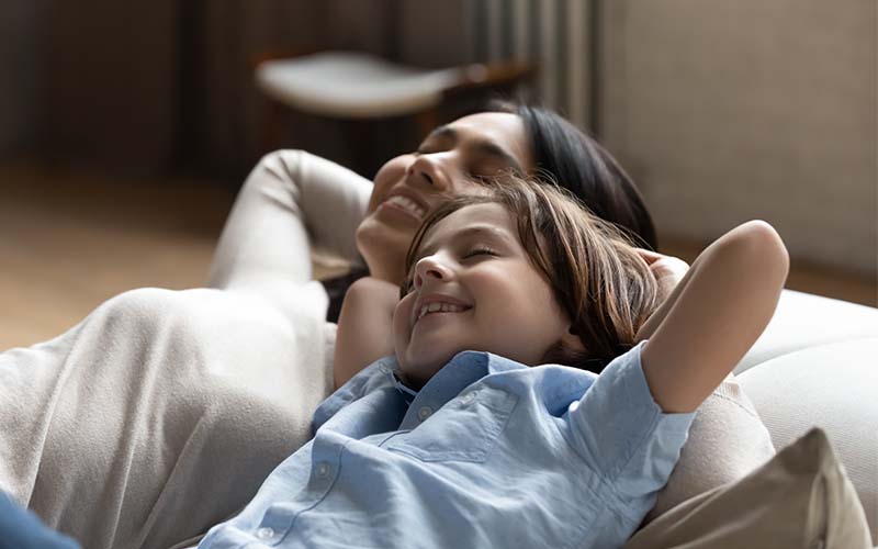 Happy young mother daydreaming napping with son enjoying spending carefree time, breathing fresh air resting together