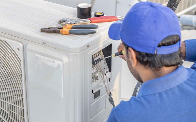 A professional AC tec is fixing a heavy duty unit of central air conditioning system