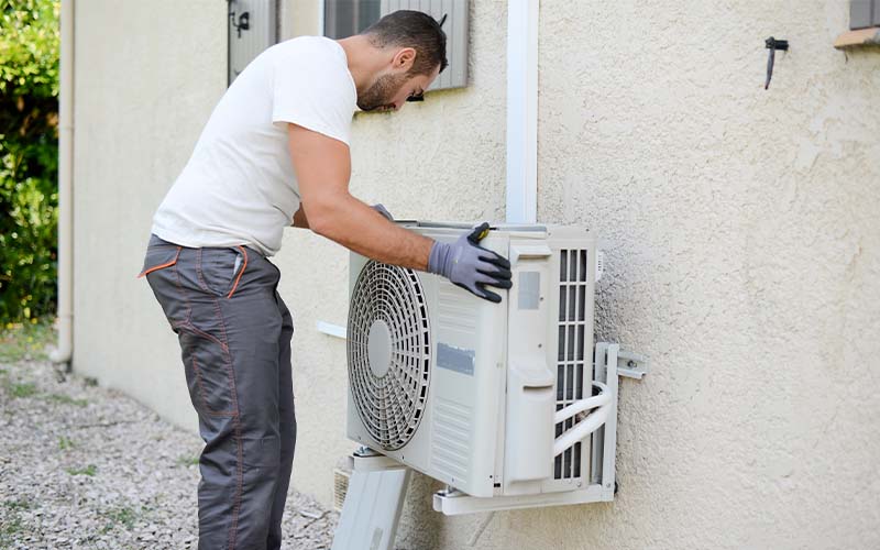 An AC technician installing an air conditioning in a client house