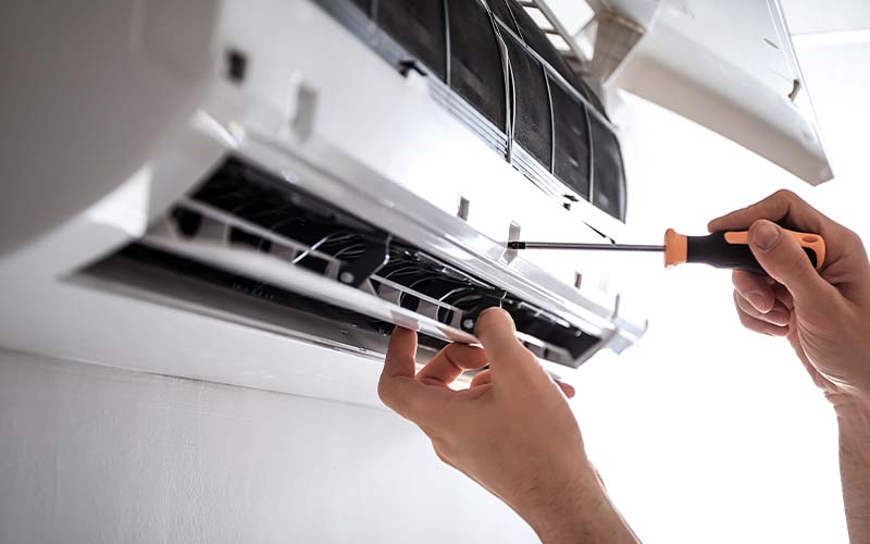 Electrician repairing air conditioner indoors