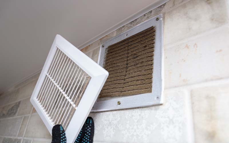 Repair service man removing a dirty air filter on a house so he can replace it with a new clean