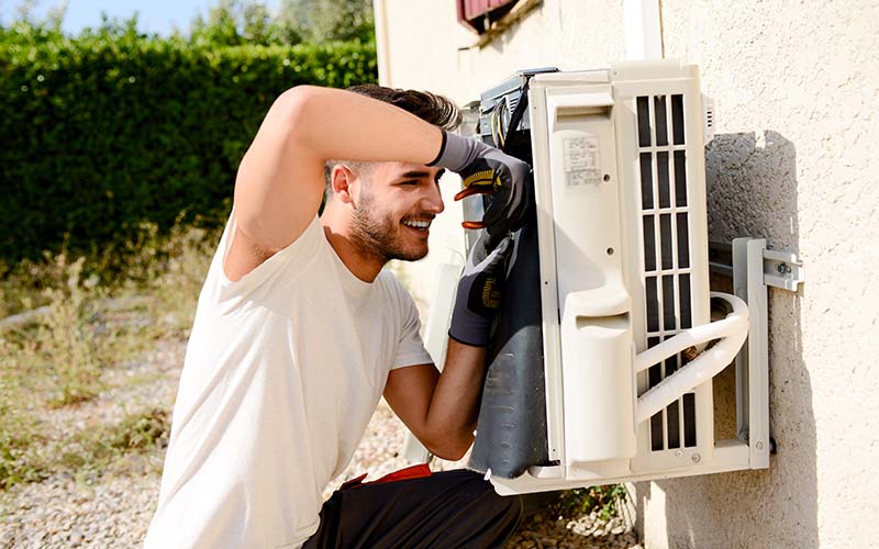 HVAC expert working on outdoor compressor unit air conditioner at a client's home