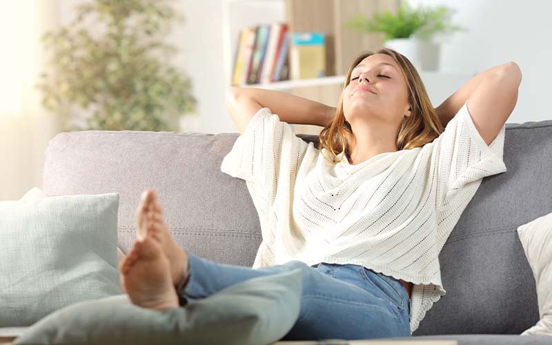 Woman relaxing sitting on a sofa at home enjoying air quality