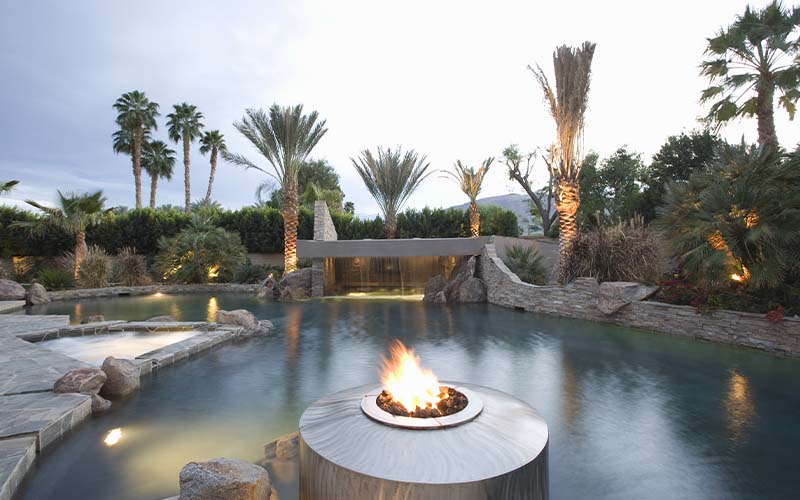 View of a luxurious swimming pool with live flame heater in foreground
